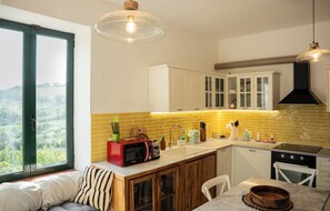 A kitchen with a large window, a microwave, a sink, and cabinets. - Villa Maline – Private country villa with a hot tub and sauna (Marche)