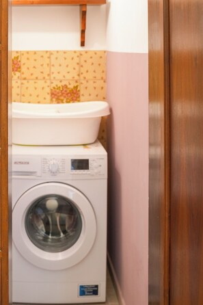Una lavadora y un lavabo blanco apilados en un rincón.