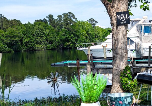 A calm lake with boats docked, a sign on a tree, and a potted plant.