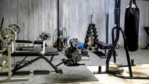 Un gimnasio con equipo de levantamiento de pesas, bancos y una estructura para sentadillas.