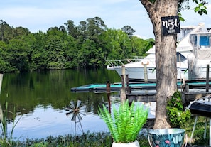 A calm lake with boats docked, a sign on a tree, and a potted plant.