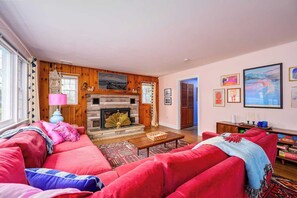 A living room with a fireplace, red sofas, a coffee table, and a bookshelf.
