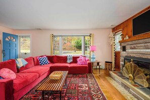 A living room with a red sofa, a patterned rug, a fireplace, and a large window.