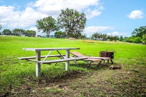 Ein Picknicktisch mit Bänken und einer kleinen Aufbewahrungsbox in einer Wiese.