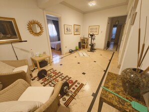 A living room with a sofa, a table, a mirror, and a ceiling fan. - Spacious 3-bedroom condo in lovely Giza Governorate with AC and fitness room (Giza Governorate)