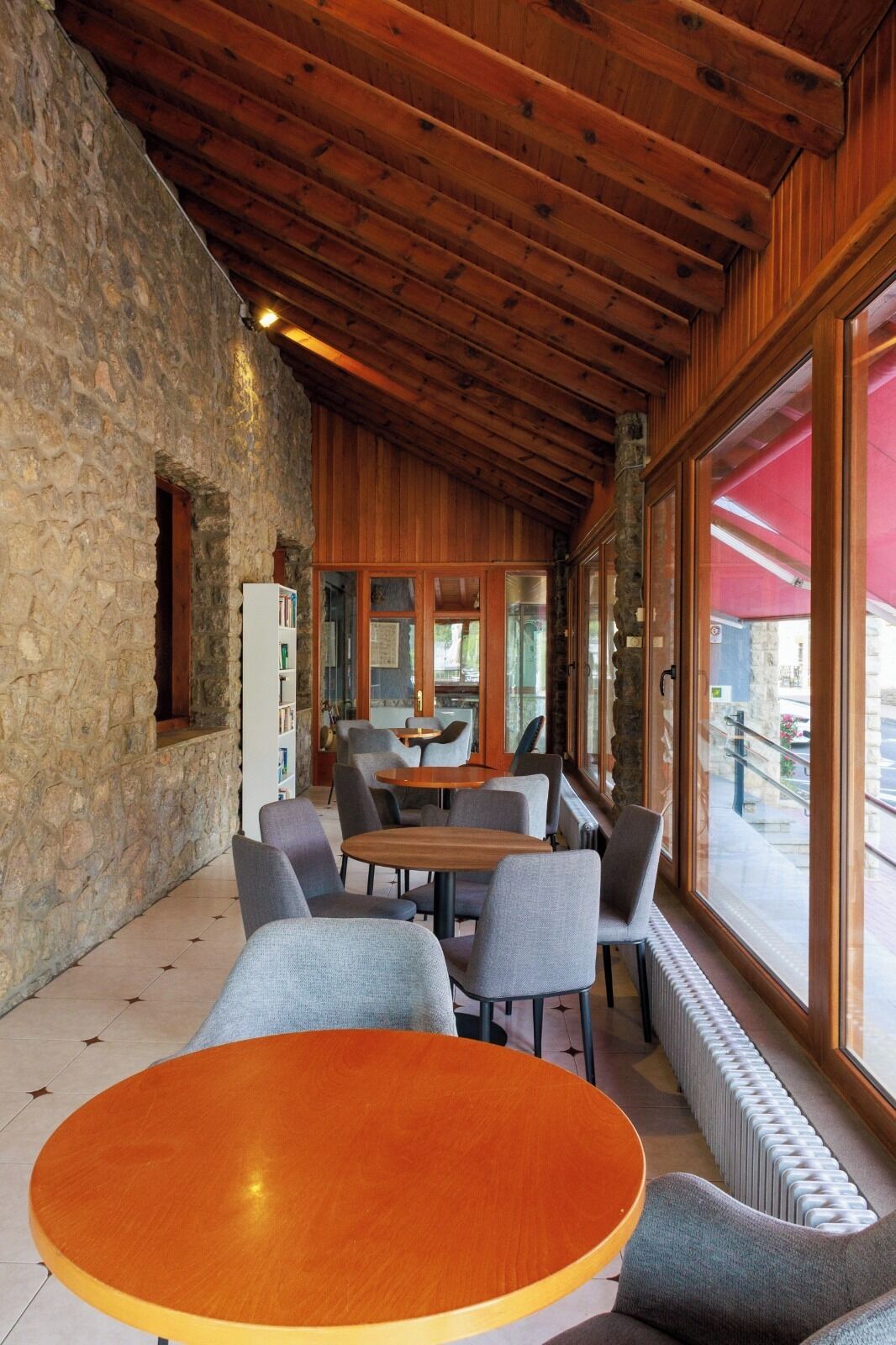 Un restaurante con paredes de piedra, vigas de madera en el techo y ventanas grandes.