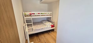 A bunk bed with a ladder, a floral bedspread, and a red pillow. - Top floor apartment with panoramic view (Antibes)