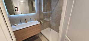 A modern bathroom with a glass-enclosed shower, a wooden vanity, and a large mirror. - Top floor apartment with panoramic view (Antibes)
