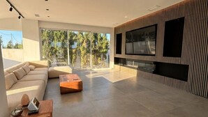 Uma sala de estar ampla, com uma televisão grande, um sofá e uma mesa de centro.