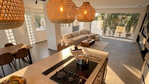 Uma cozinha moderna com ilha central, luminárias pendentes e vista para o exterior.