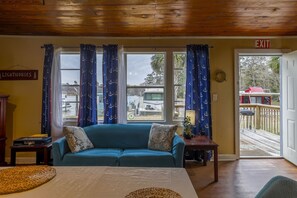 Une pièce avec un canapé bleu, un plafond en bois et une vue sur l’extérieur.