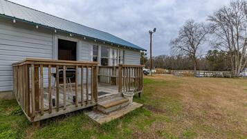 A single-story building with a porch, a garage door, and a grassy yard.