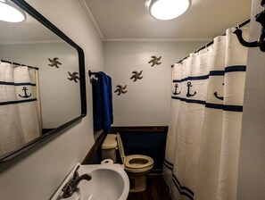 A compact bathroom with a toilet, sink, and mirror.
