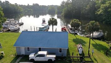 A house with a blue roof, a white truck, and a boat docked at a marina.