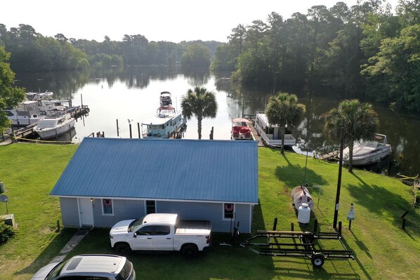 A house with a blue roof, a white truck, and a boat docked at a marina.