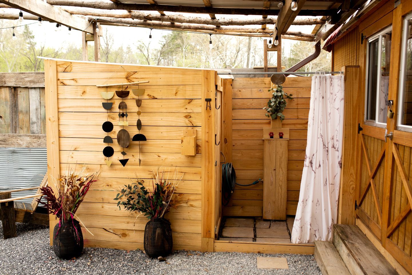 A wooden structure with a door, a hanging light fixture, and two potted plants.