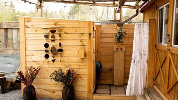 A wooden structure with a door, a hanging light fixture, and two potted plants.