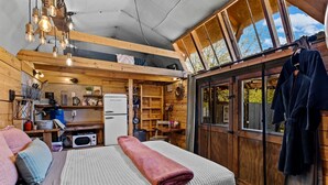 A cozy cabin interior with a bed, kitchenette, and wooden walls.