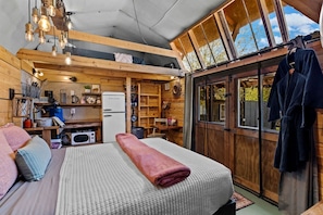 L’intérieur d’un chalet confortable, avec un lit, un coin cuisine et des murs en bois.
