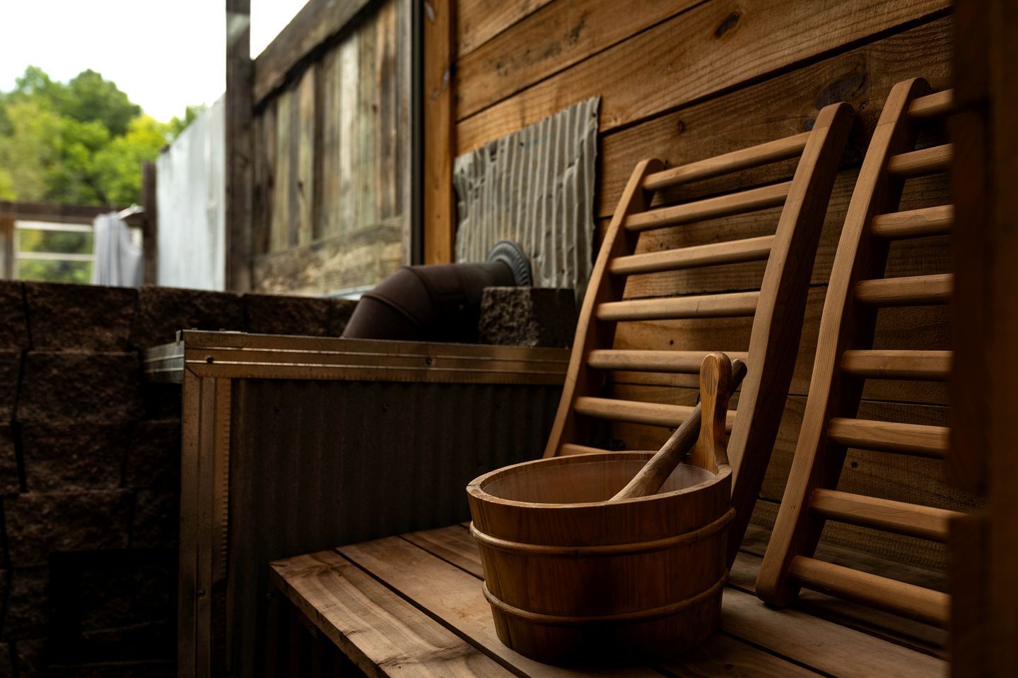 A wooden sauna with a wooden bench, a wooden bucket, and a wooden ladle.