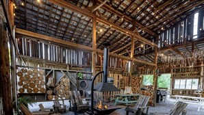 A rustic interior with a fireplace, wooden furniture, and a high ceiling with exposed beams.