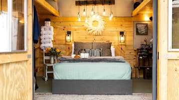 Een gezellige slaapkamer met een bed, houten wanden, een hanglamp en een zonvormige decoratie.