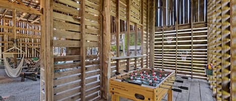 A wooden structure with a foosball table, a hammock, and a basketball hoop.