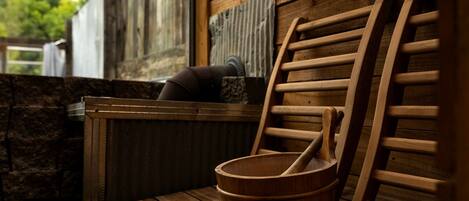 A wooden sauna with a wooden bench, a wooden bucket, and a wooden ladle.