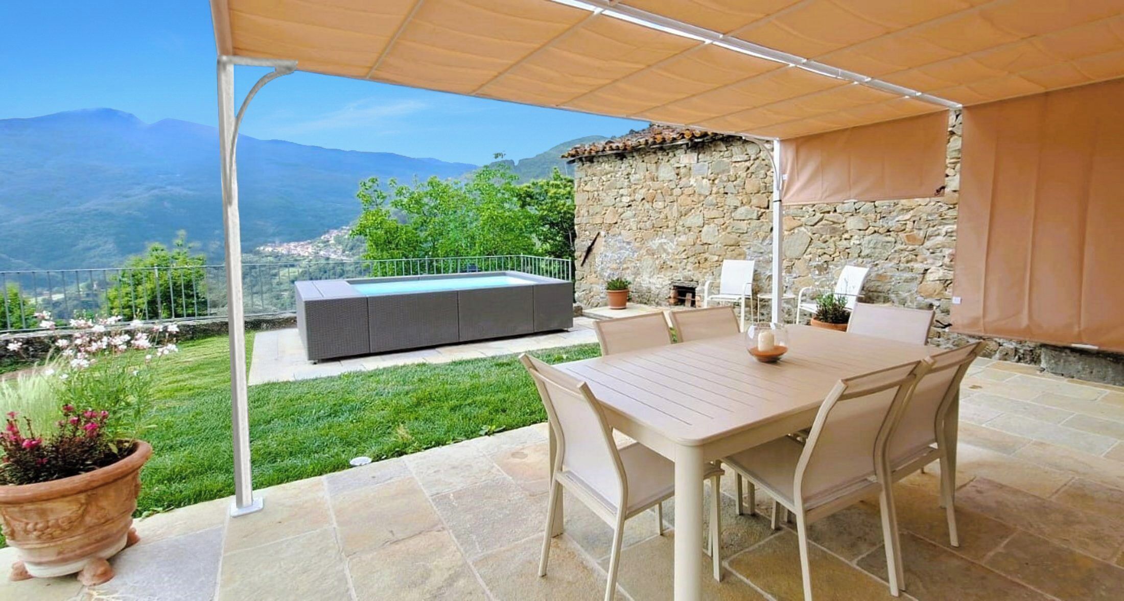 An outdoor patio with a table and chairs, a stone wall, and a view of mountains.