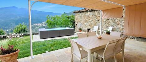 An outdoor patio with a table and chairs, a stone wall, and a view of mountains.