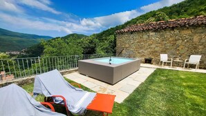 Ein Pool mit einer Steinmauer, einer Rasenfläche und Blick auf die Berge.