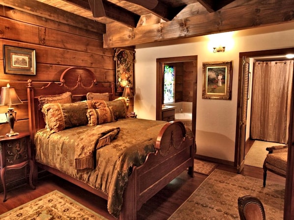 A traditional wooden bedroom with a four-poster bed, a nightstand, a chair, and a small table.