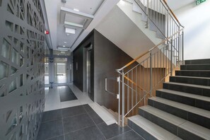 Eine moderne Hotelhalle mit Treppe, Glastrennwand und Empfangsbereich.