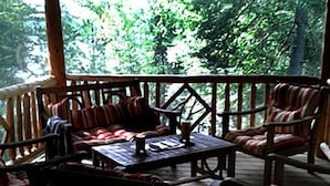 Una terraza de madera con mobiliario exterior, incluyendo sillas y una mesa.