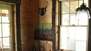 Un interior de madera con una mesa de comedor, sillas, una lámpara colgante y un ventanal.