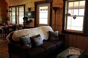 Una habitación acogedora con detalles de madera, un ventanal con un adorno de corazón y un sofá con varios cojines.
