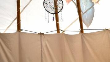 A bed with a patterned bedspread, multiple pillows, and a dreamcatcher hanging from the ceiling.