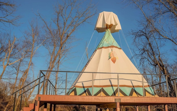 A conical tent structure with a canopy, supported by a metal frame, set against a backdrop of leafless trees. - Serene Teepee Escape with Soulful Ambiance in Salt Lick, Kentucky (Salt Lick)