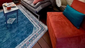 A cozy interior with a sofa, a red couch, a small table, and a lamp.