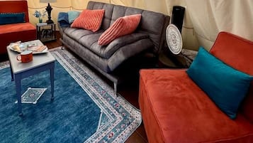 A cozy interior with a sofa, a red couch, a small table, and a lamp.