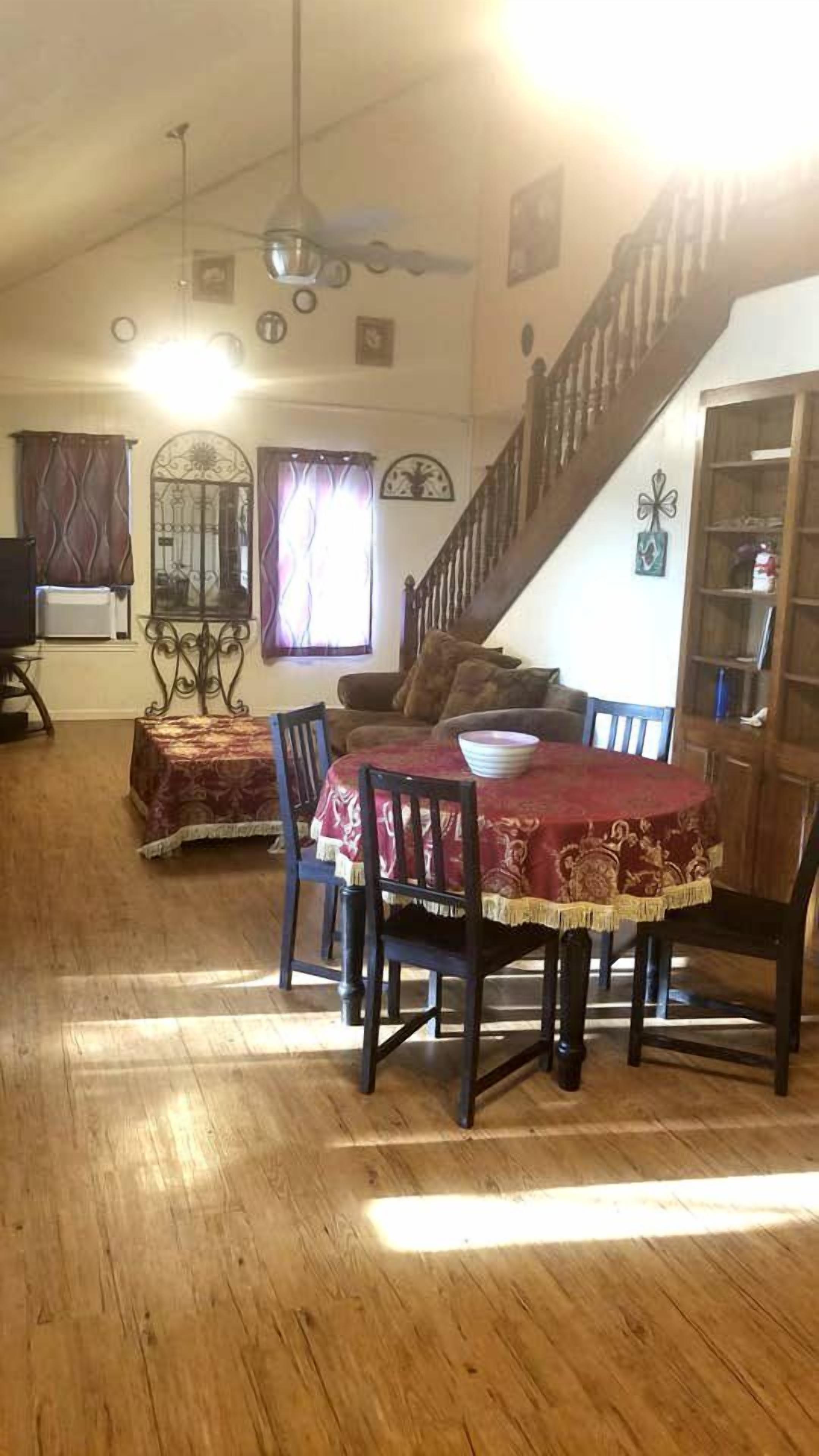A dining area with a wooden table and chairs, a staircase, and a bookshelf.