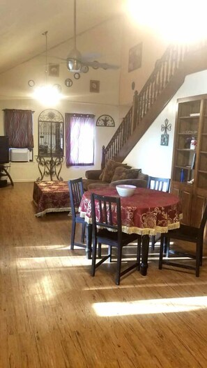 A dining area with a wooden table and chairs, a staircase, and a bookshelf.