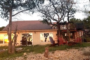A rustic cabin with a large porch, a wooden deck, and a staircase leading to a second level.