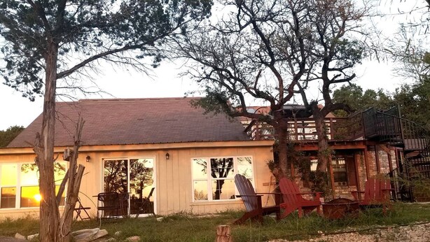 Un chalet rustique doté d’une grande véranda, d’une terrasse en bois et d’un escalier menant à un deuxième étage.