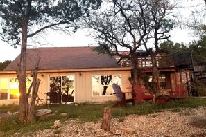 A rustic cabin with a large porch, a wooden deck, and a staircase leading to a second level.