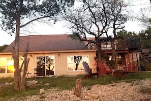 A rustic cabin with a large porch, a wooden deck, and a staircase leading to a second level.