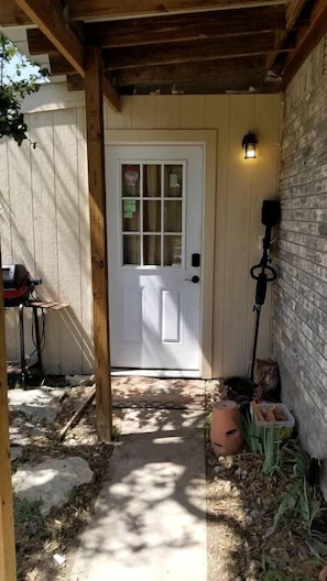 A wooden door with a white panel, a lantern, and a brick wall.