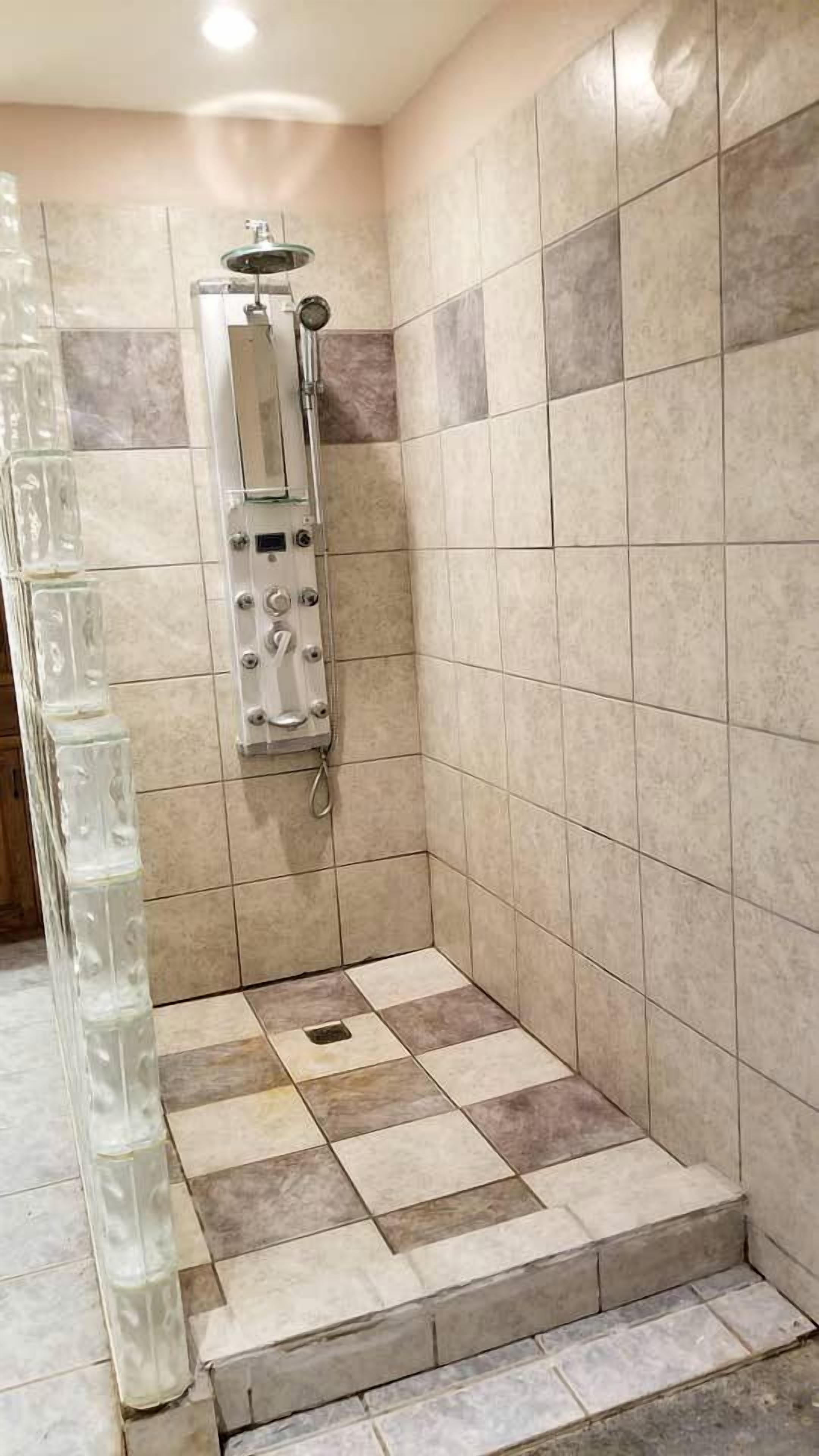 A shower area with tiled walls and a showerhead.