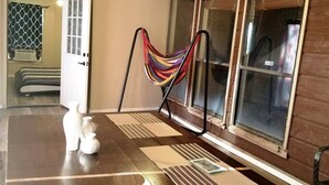Une pièce dotée d’une grande fenêtre, d’un hamac, d’une porte et d’une petite table agrémentée d’objets décoratifs.