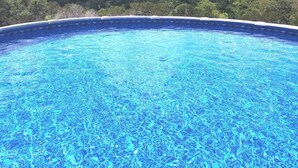 Une piscine d’un bleu éclatant, offrant une vue sur un paysage boisé.